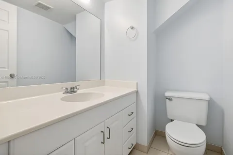 a bathroom with a toilet sink vanity granite and mirror