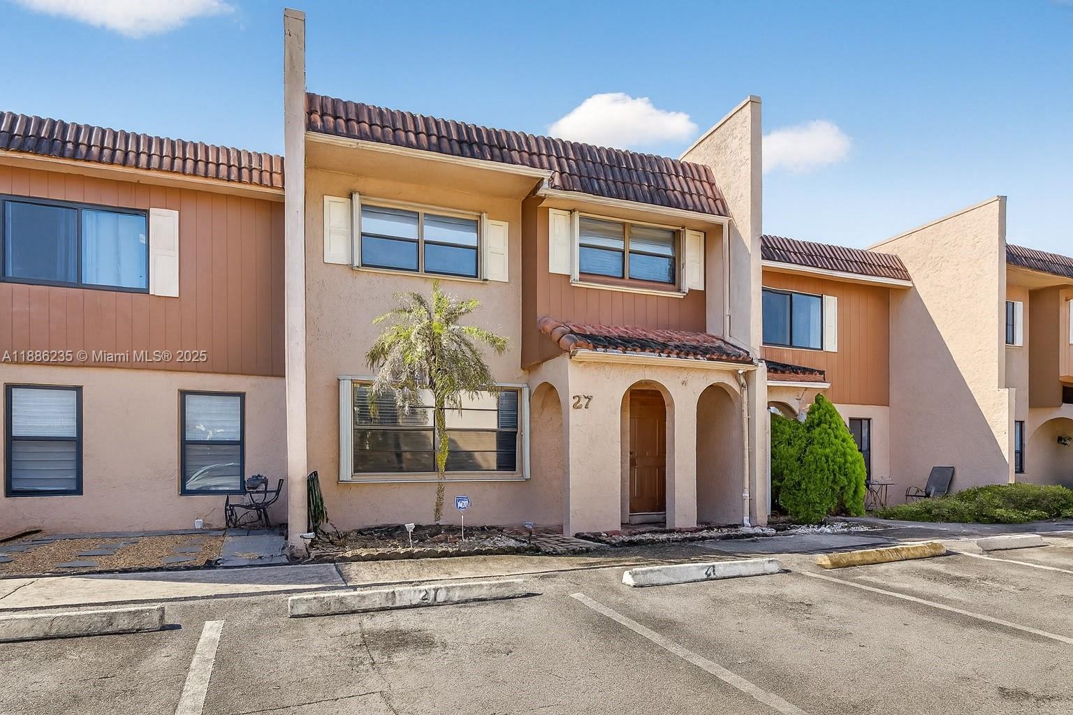 27 Madrid Lane, Unit 28 Davie, FL 33324 - Photo 3 of 34 a front view of a house with a yard and garage