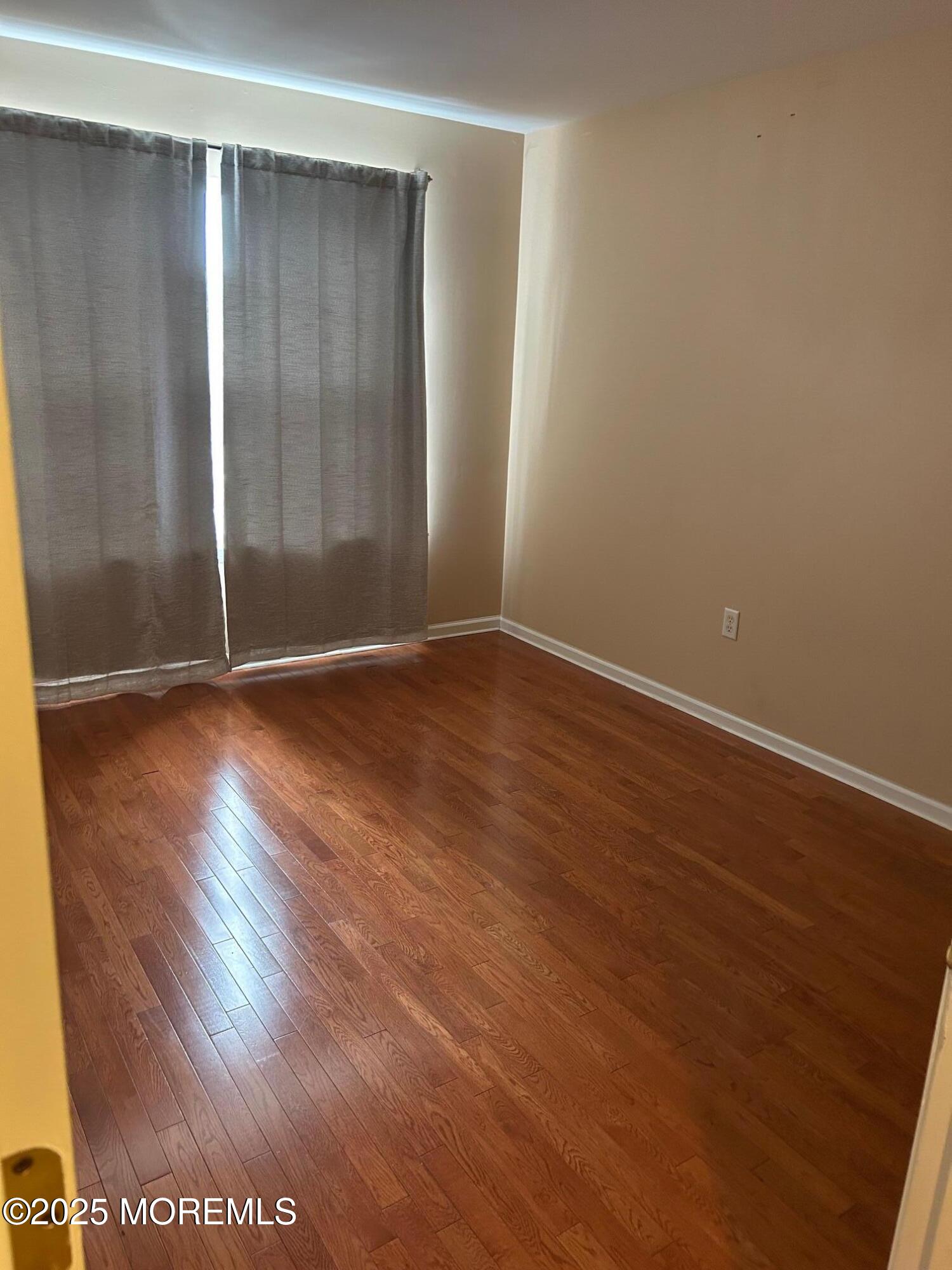 319 Bernard Drive Morganville, NJ 07751 - Photo 20 of 32 a view of an empty room with wooden floor and a window