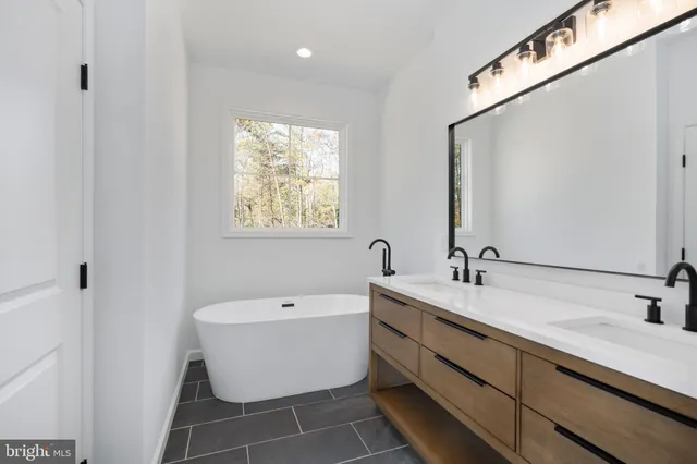 a bathroom with a double vanity sink a mirror and bathtub