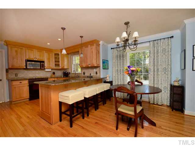 7201 Grist Mill Road Raleigh, NC 27615 - Photo 7 of 25 a open kitchen with stainless steel appliances granite countertop a stove refrigerator and a dining table with wooden floor