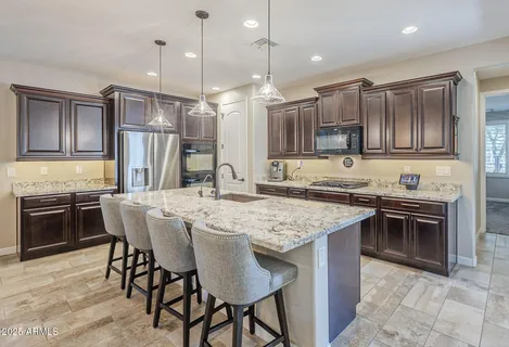 a kitchen with kitchen island granite countertop a stove a sink a oven a dining table and chairs