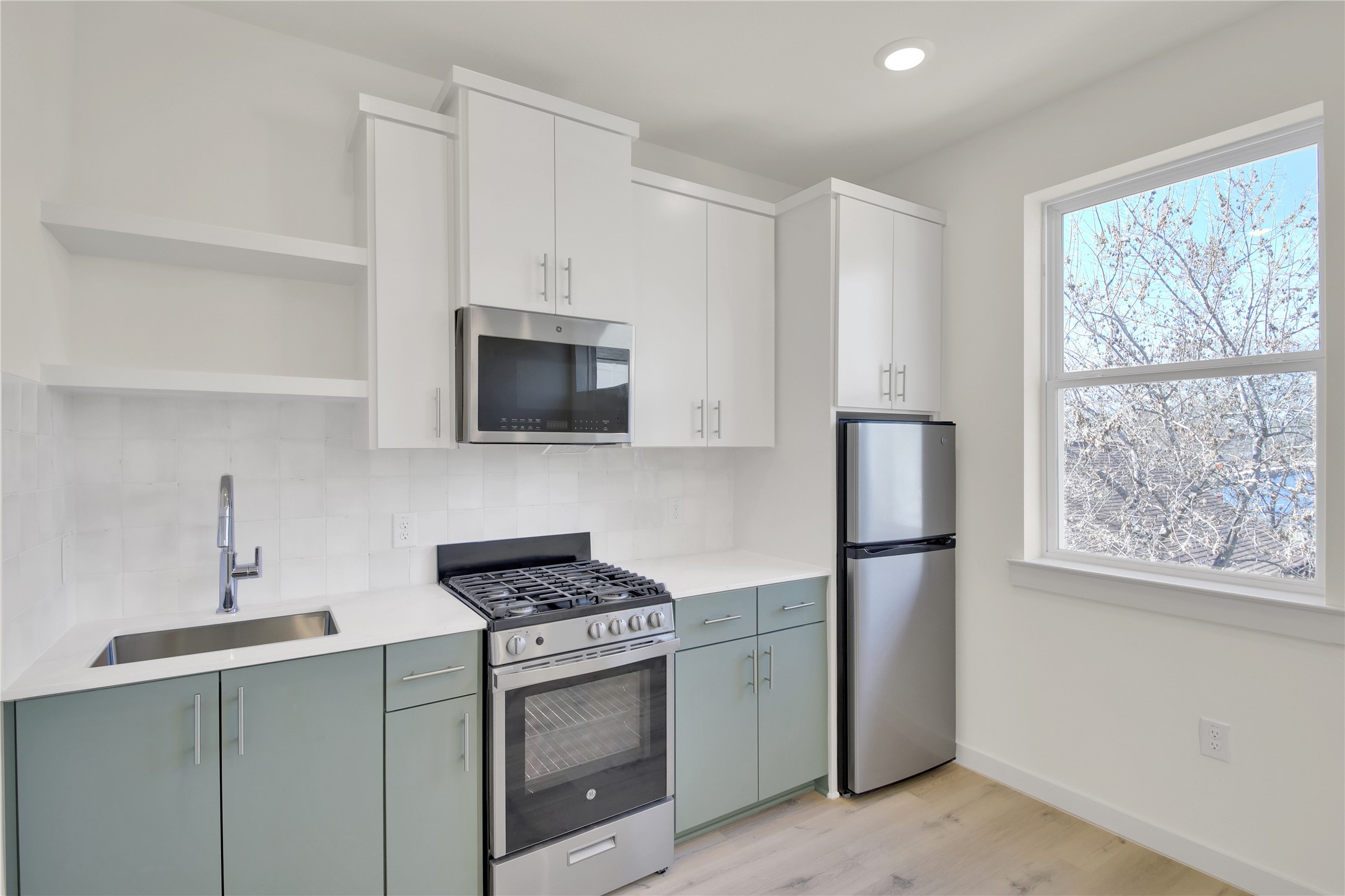 6802 Montana Street, Unit 2 Austin, TX 78741 - Photo 7 of 11 Kitchen featuring dual tone cabinets, open shelves, stainless steel appliances, tasteful backsplash, and light wood finished floors