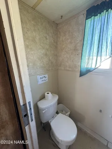 a white toilet sitting next to a small window