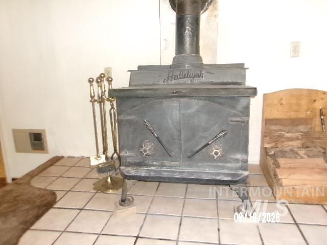 31997 2nd Fork Road Ola, ID 83657 - Photo 11 of 47 Cast iron wood-burning stove with decorative brass tools and a tiled floor surround