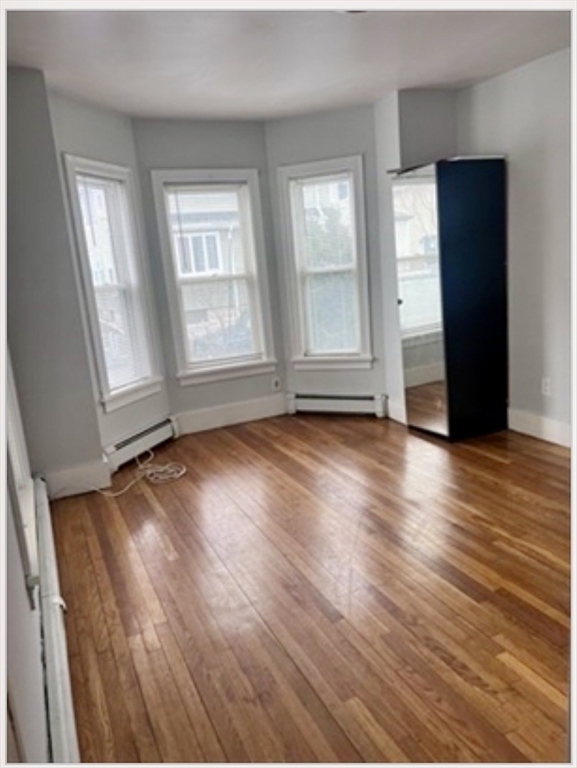 18 West Street, Unit A Everett, MA 02149 - Photo 6 of 10 an empty room with wooden floor and windows