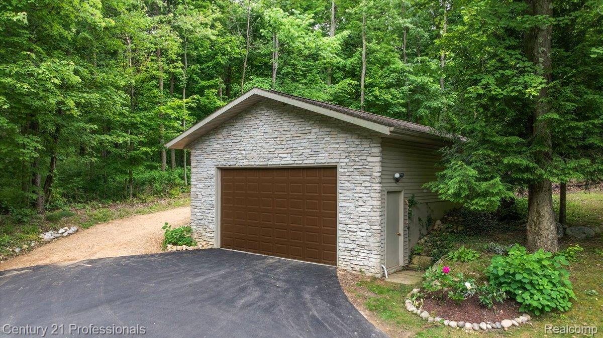9867 Rainbow Ridge Drive Schoolcraft, MI 49087 - Photo 14 of 82 Detached garage featuring stone veneer siding, a paneled brown garage door, and an asphalt driveway