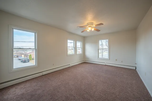an empty room with windows and chandelier fan