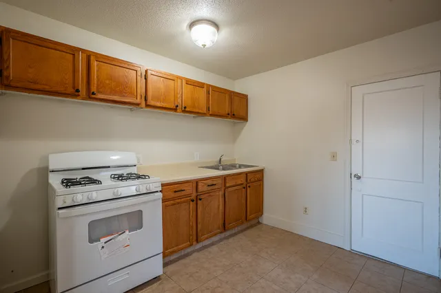 a kitchen with granite countertop a stove top oven sink and cabinets