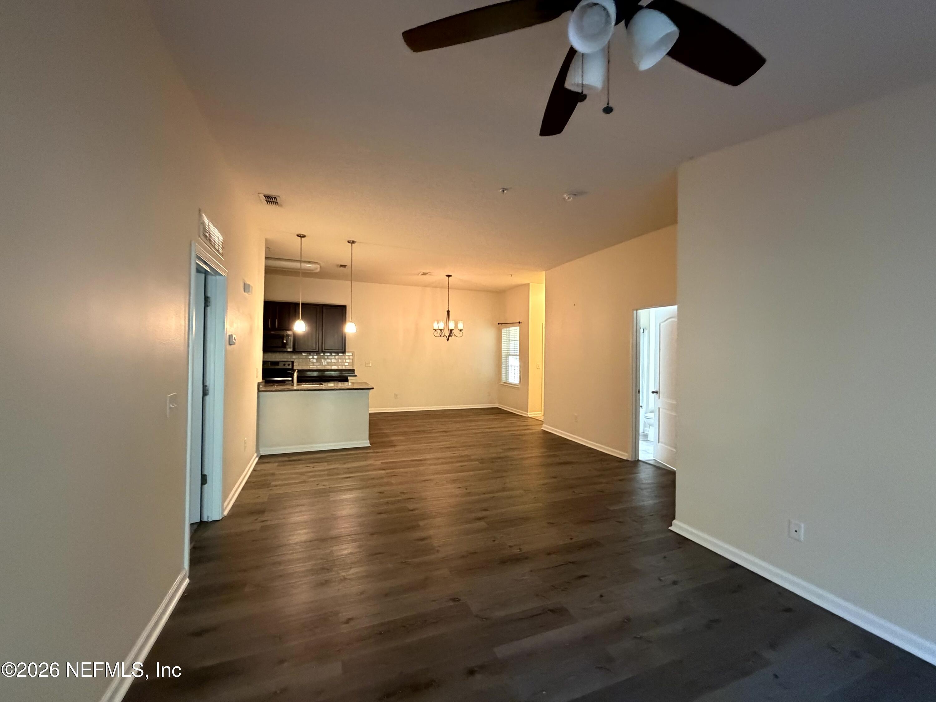1717 Golden Lake Loop St. Augustine, FL 32084 - Photo 19 of 24 an empty room with wooden floor kitchen view and a refrigerator