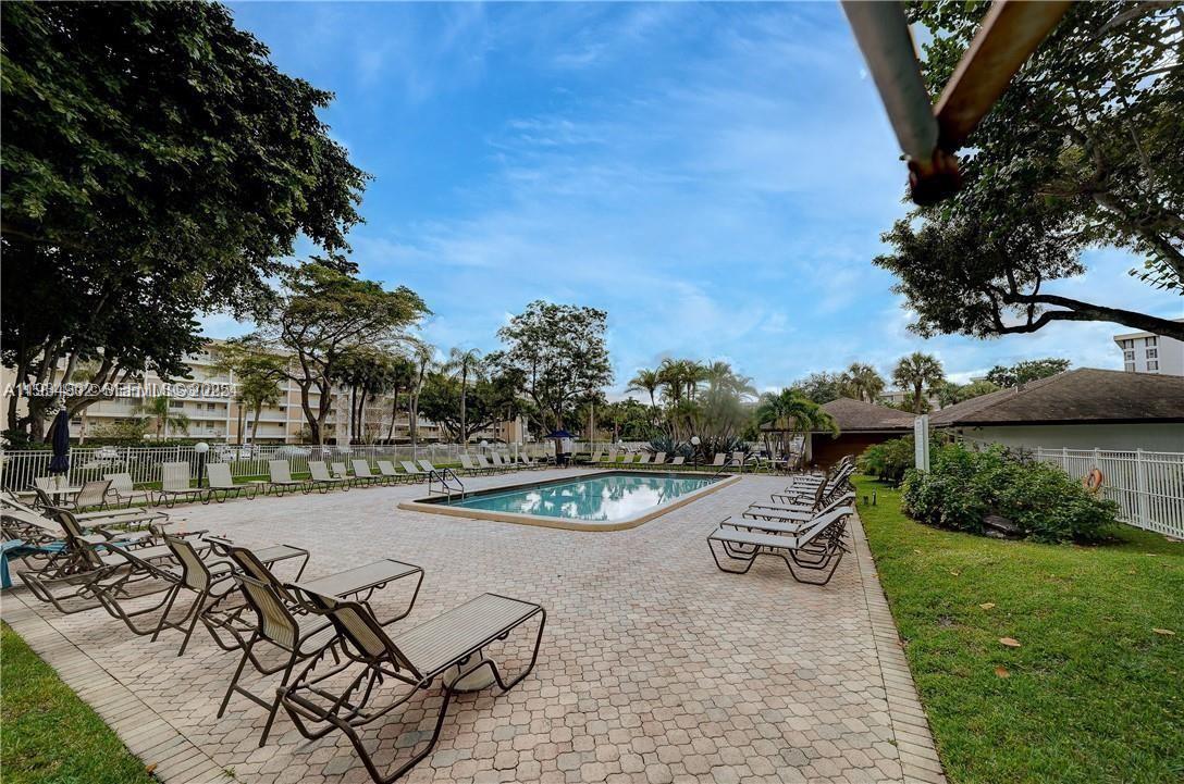 2671 South Course Drive, Unit 109 Pompano Beach, FL 33069 - Photo 31 of 39 a view of a backyard with table and chairs with wooden fence and plants