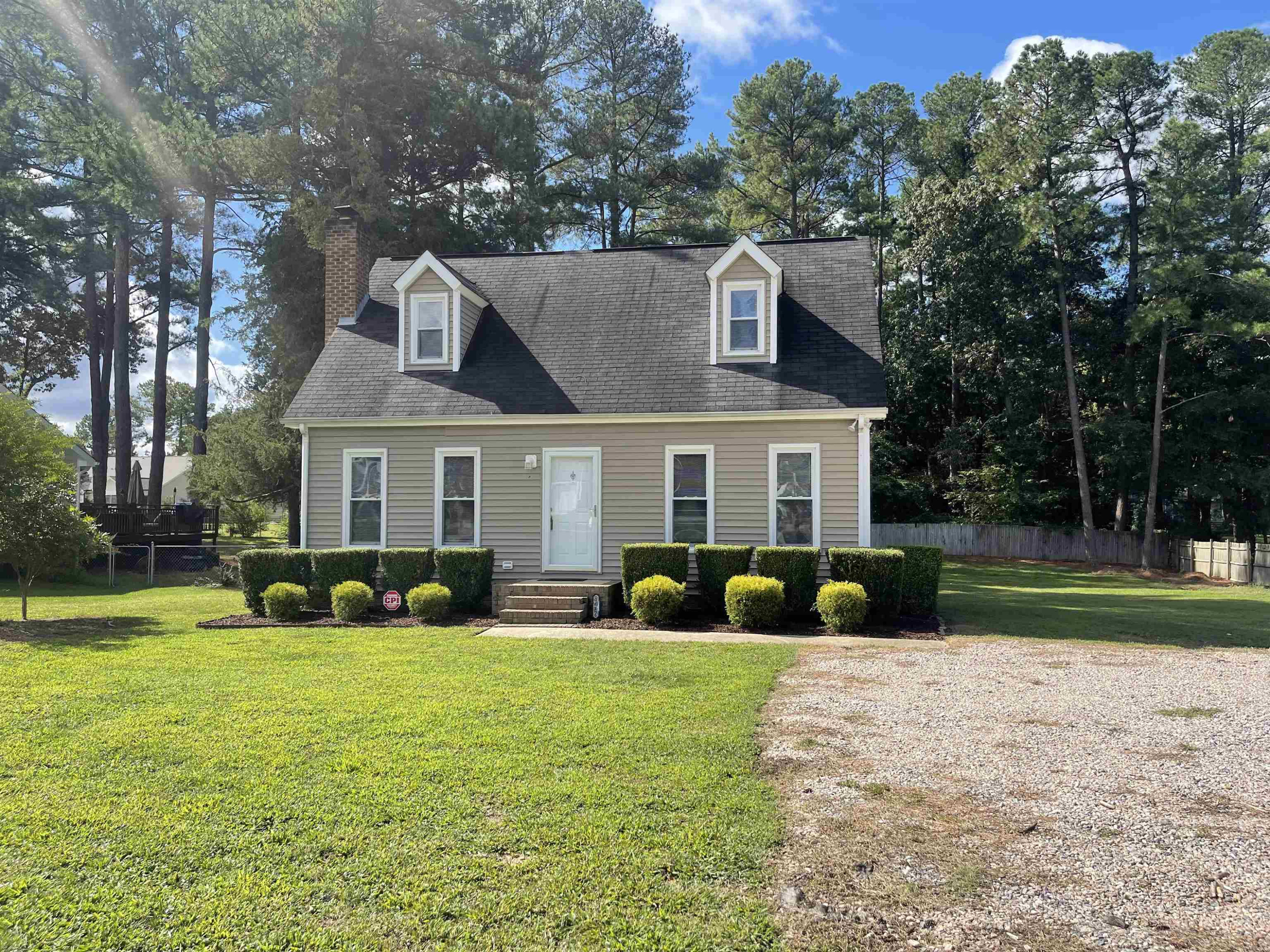 a front view of a house with garden and trees