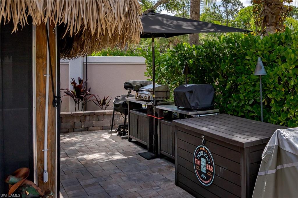 13571 Snook Circle Naples, FL 34114 - Photo 11 of 47 a view of a patio with table and chairs under an umbrella with a small yard