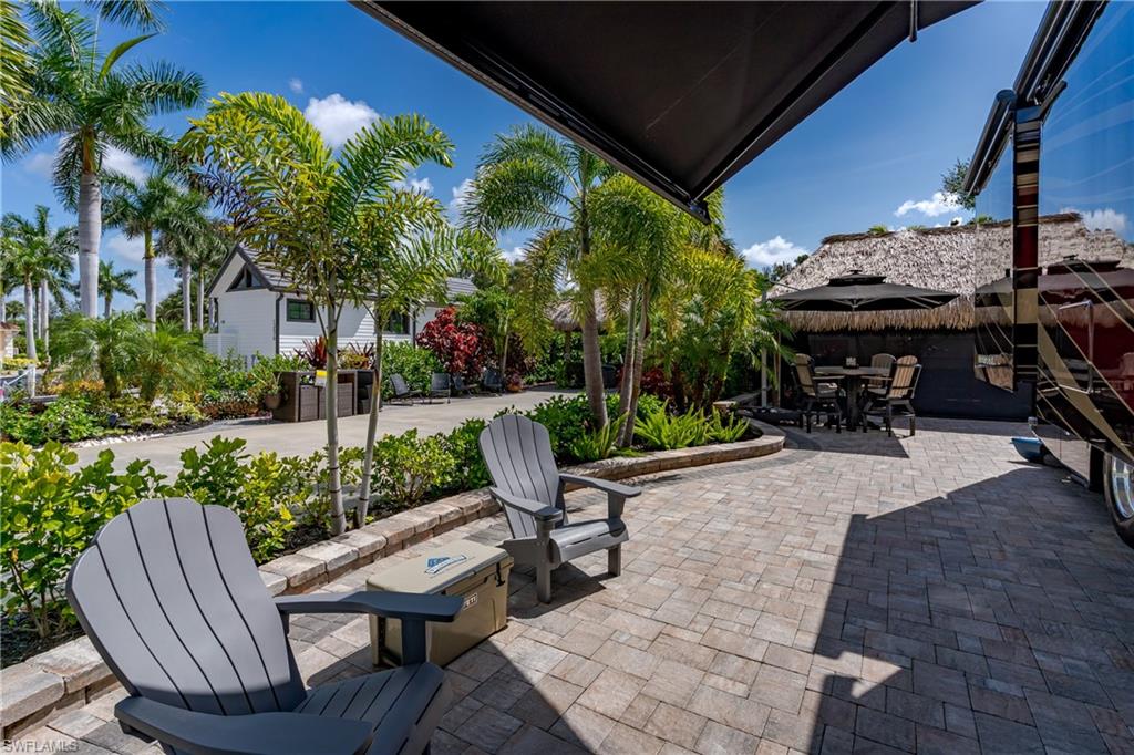 13571 Snook Circle Naples, FL 34114 - Photo 21 of 47 a view of a patio with table and chairs potted plants and a palm tree