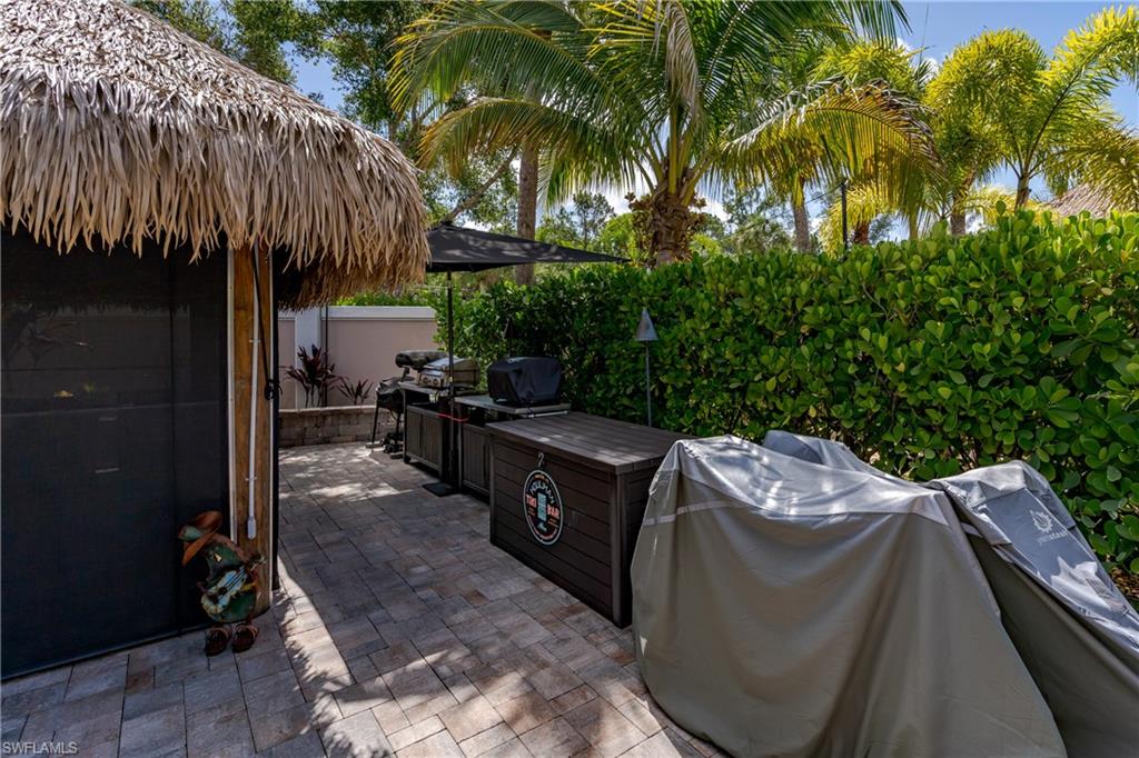 13571 Snook Circle Naples, FL 34114 - Photo 10 of 47 a backyard of a house with table and chairs under an umbrella