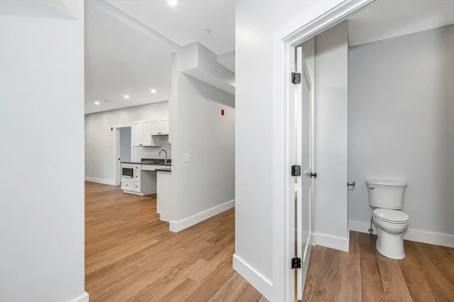 a view of a hallway with wooden floor and a bathroom view