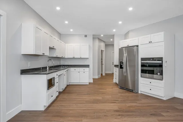a kitchen with stainless steel appliances kitchen island granite countertop a refrigerator and a stove top oven