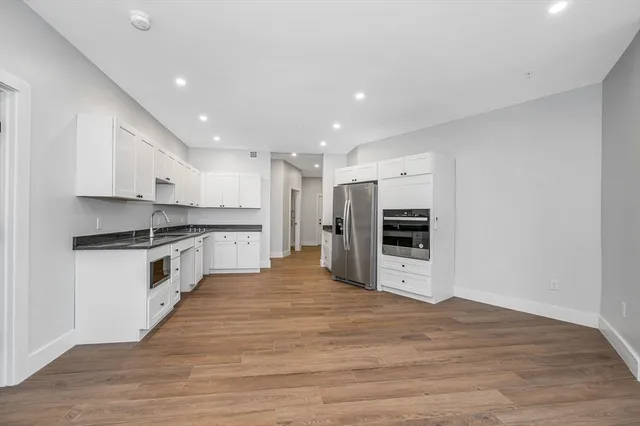 a large white kitchen with stainless steel appliances granite countertop a stove and a refrigerator