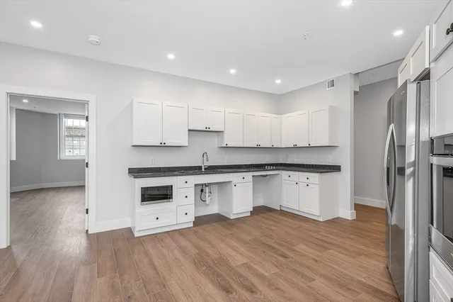 a kitchen with stainless steel appliances granite countertop a refrigerator sink and white cabinets