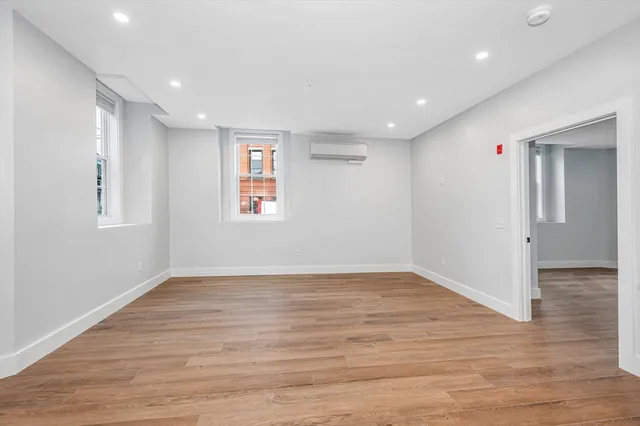 an empty room with wooden floor and windows