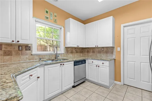 a kitchen with granite countertop white cabinets and stainless steel appliances