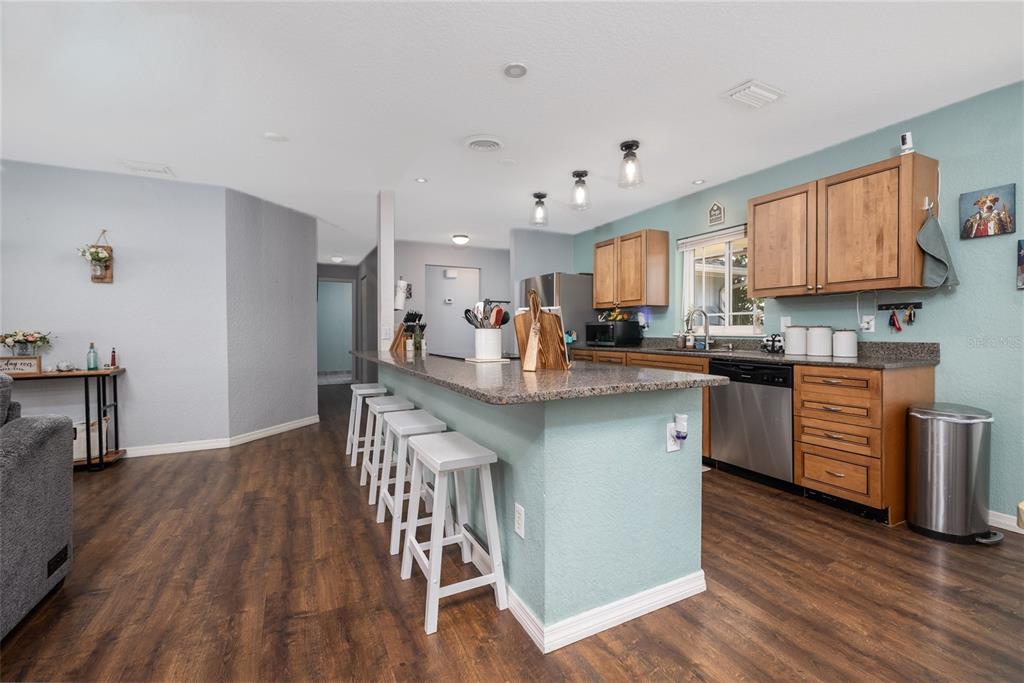 1709 Umbrella Tree Drive Edgewater, FL 32132 - Photo 11 of 37 a kitchen with stainless steel appliances granite countertop a refrigerator a stove top oven a sink dishwasher and a dining table with wooden floor