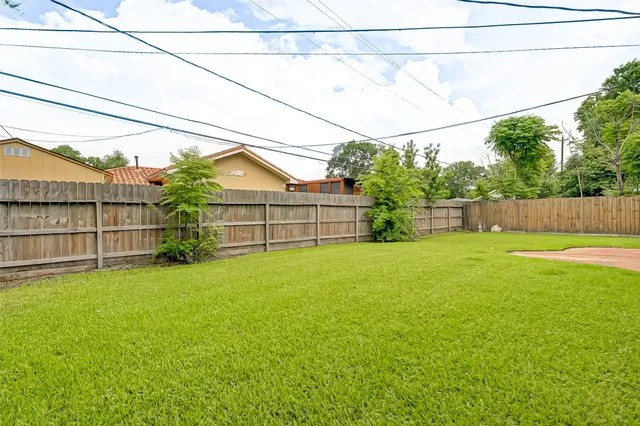 a view of a backyard with plants and wooden fence