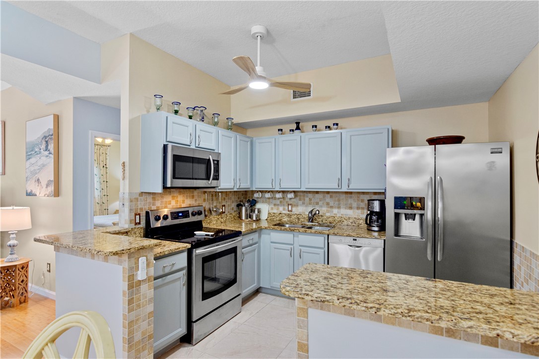 528 7th Square Southwest, Unit 102 Vero Beach, FL 32962 - Photo 5 of 28 a kitchen with granite countertop a refrigerator a sink dishwasher a stove and a refrigerator with wooden floor