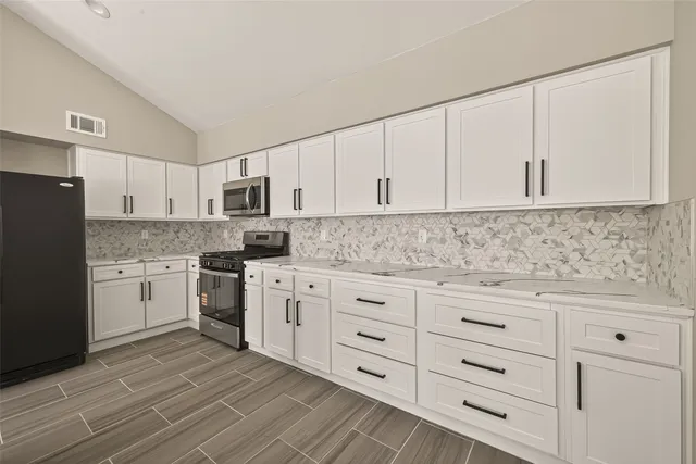 a kitchen with granite countertop white cabinets and stainless steel appliances