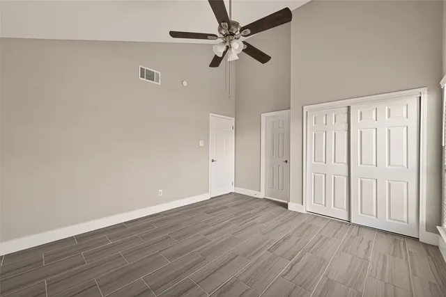an empty room with wooden floor fan and windows