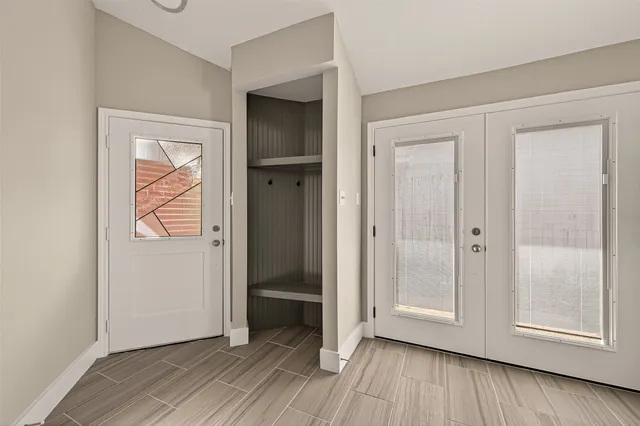 an empty room with wooden floor closet and windows
