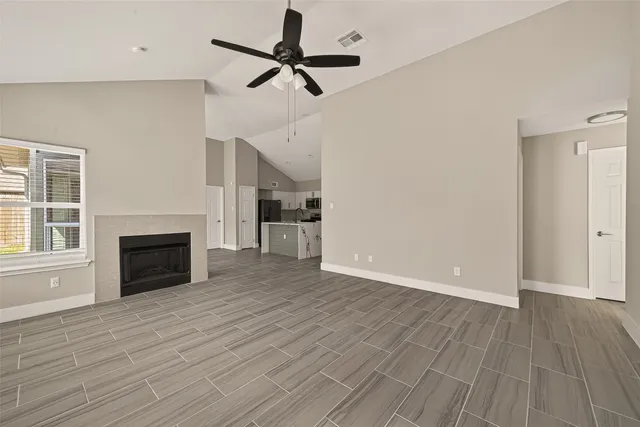 an empty room with wooden floor fireplace and windows