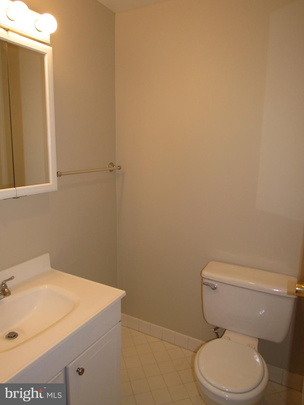 11200 Chestnut Grove Square, Unit 303 Reston, VA 20190 - Photo 18 of 30 a white toilet sitting next to a white sink and vanity
