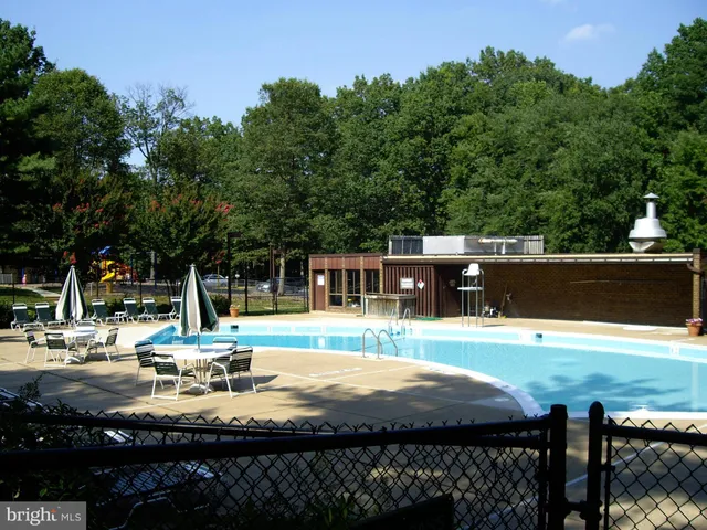 a view of a swimming pool with lawn chairs under an umbrella