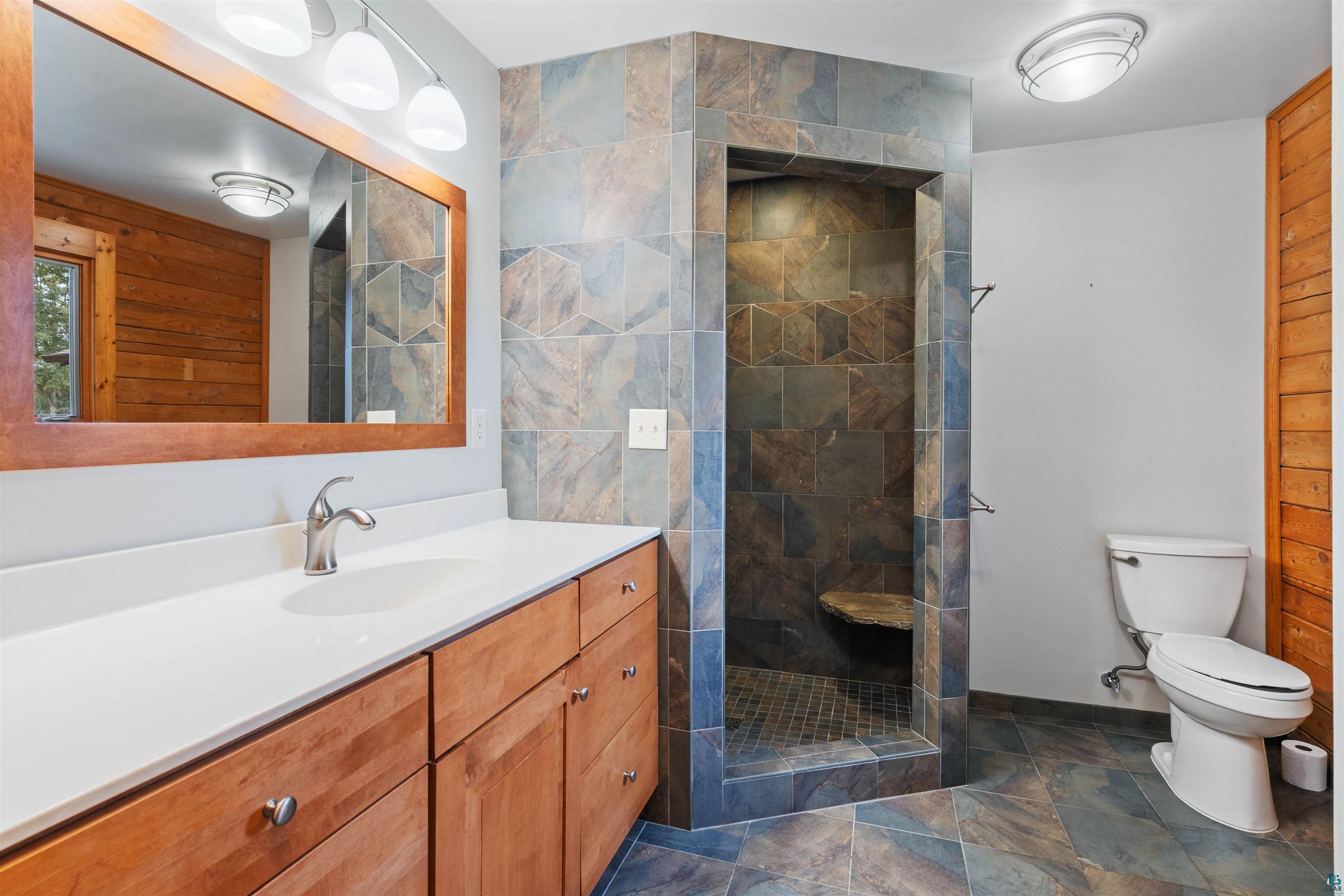 5373 Lester River Road Duluth, MN 55804 - Photo 16 of 39 Walk-in shower with natural stone tile surround and integrated bench