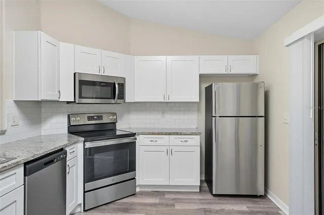 a kitchen with white cabinets and stainless steel appliances