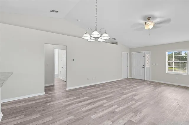 a view of an empty room with a chandelier fan