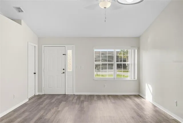 an empty room with wooden floor and windows