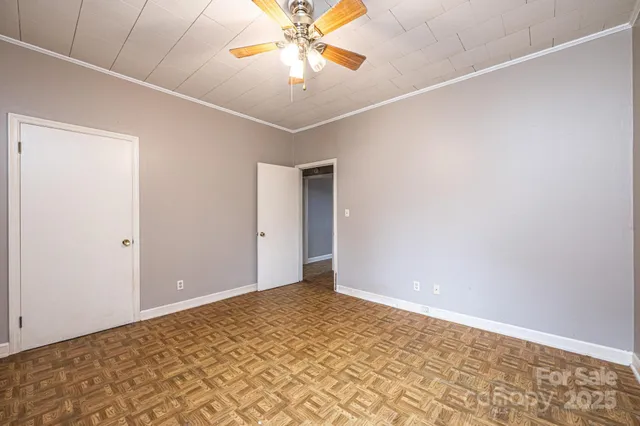 an empty room with a chandelier fan and closet