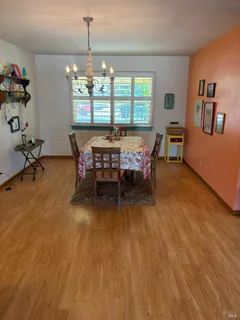 a dining room with wooden floor a chandelier a glass table and chairs
