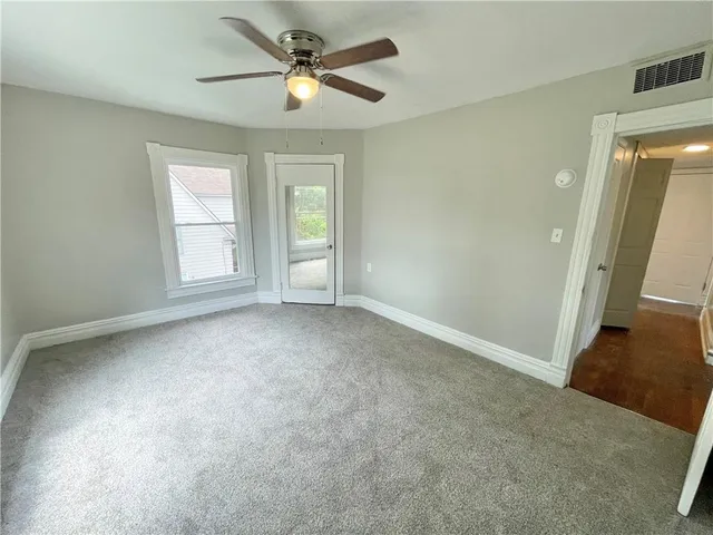 an empty room with windows and fan