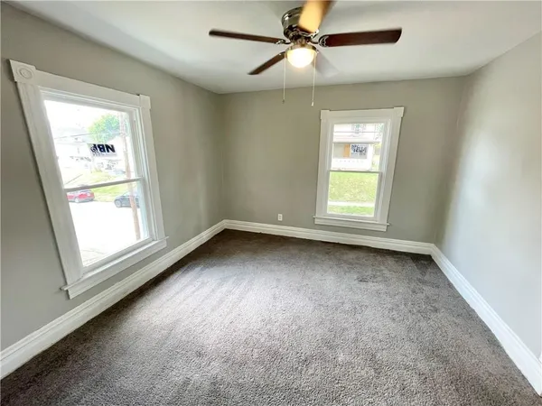 an empty room with a window and a ceiling fan