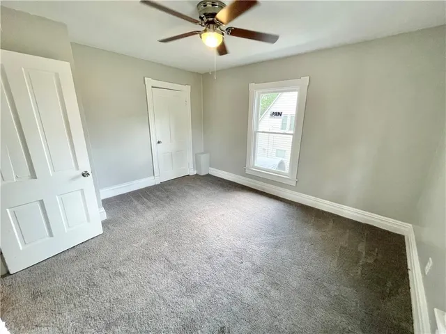 an empty room with windows and fan