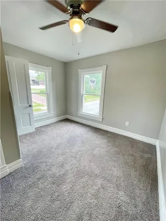 an empty room with windows and ceiling fan