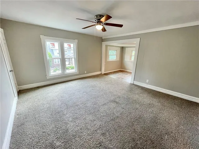 an empty room with windows and ceiling fan