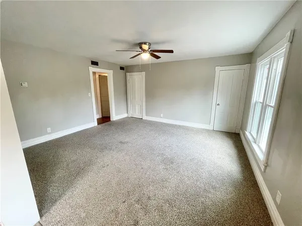 an empty room with windows and fan