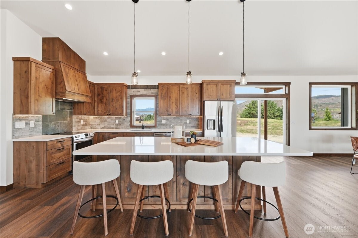 110 Slide View Lane Manson, WA 98831 - Photo 11 of 38 a kitchen with stainless steel appliances granite countertop a stove a sink a microwave a dining table and chairs with wooden floor