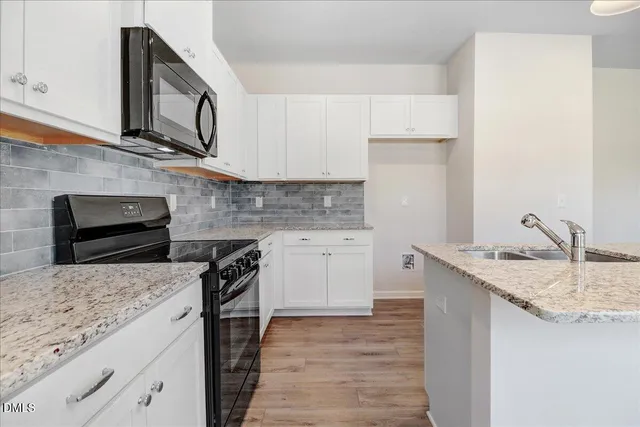 a kitchen with granite countertop a sink stove and cabinets