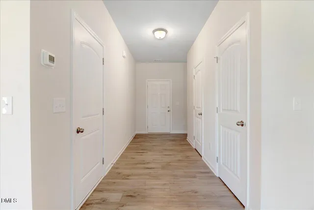 a view of a hallway with wooden floor and closet area