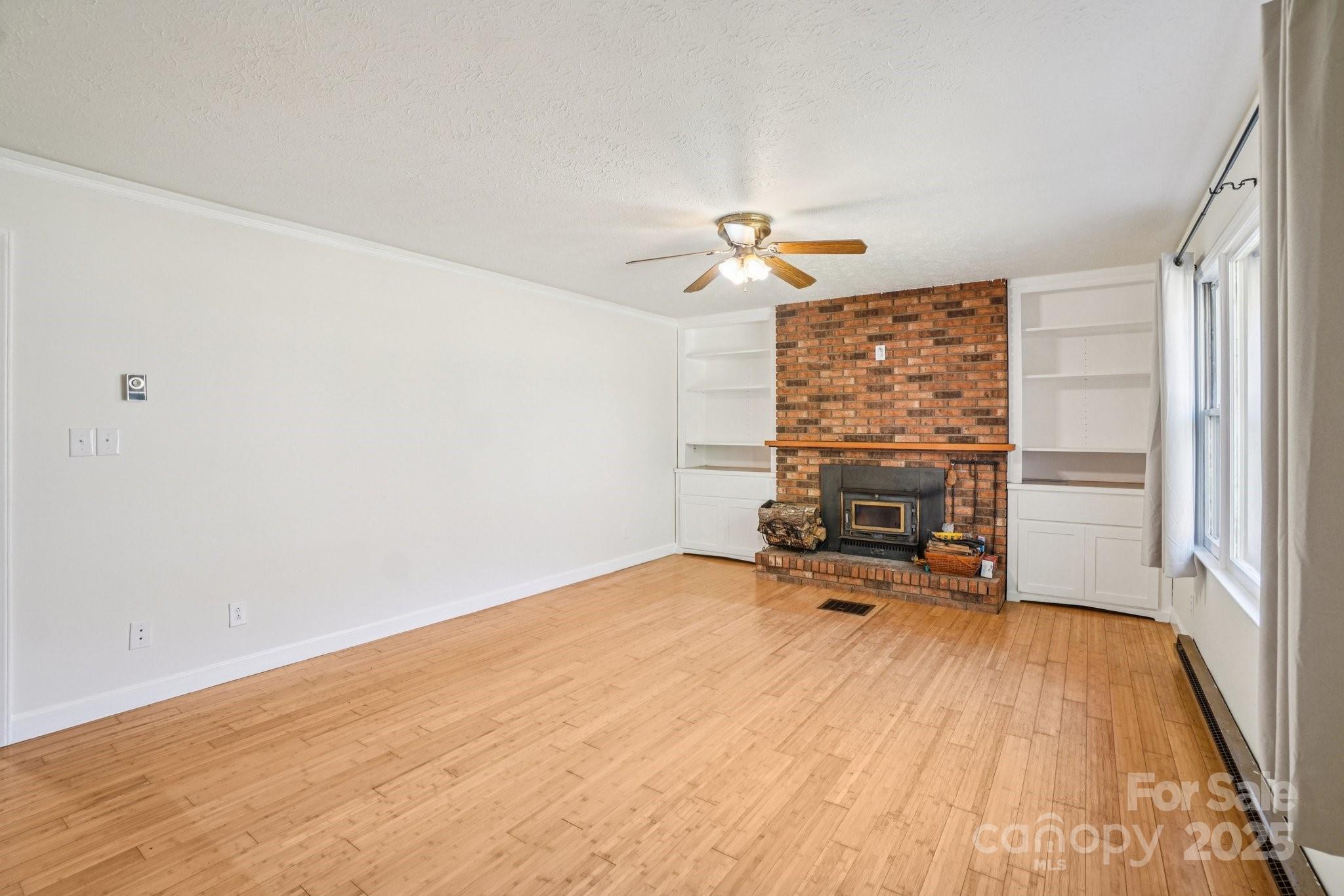 480 Paint Fork Road Barnardsville, NC 28709 - Photo 8 of 43 a view of empty room with fireplace and wooden floor